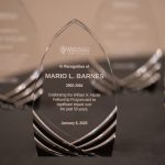 Photo of award closeup - a glass wedge in the shape of an arch with Mario L. Barnes etched onto it.