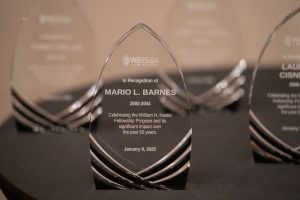 Photo of award closeup - a glass wedge in the shape of an arch with Mario L. Barnes etched onto it.