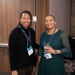 Event participants, both women of color, smiling to the camera.