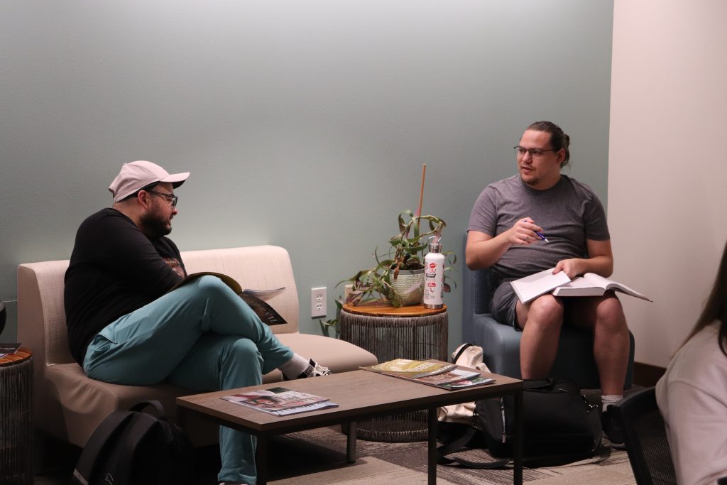 Students chat while seated in low chairs.