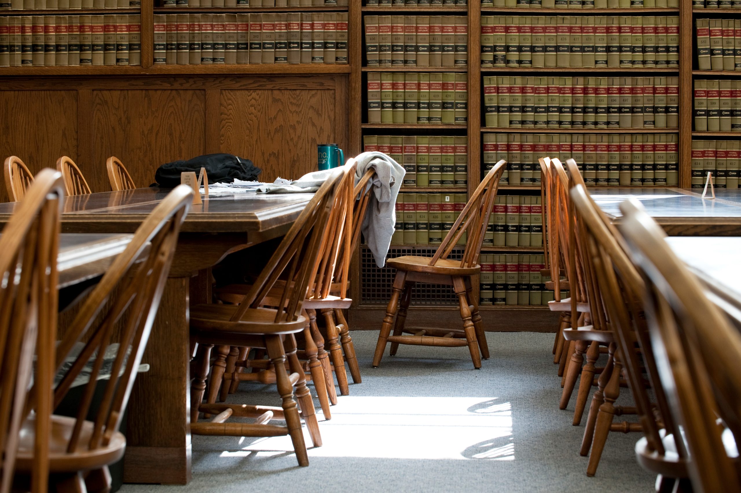 Photo of interior of Law Library with empty chairs lining tables. One chair is pulled out farther than the others.