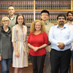 A group of people standing around a woman wearing red.