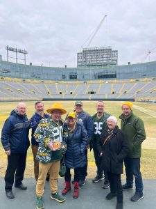 A gathering of people in coats on the Packers football field.