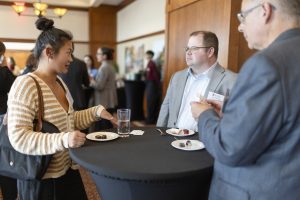 A woman gestures while speaking at a table with two men.