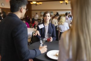 A woman speaks to colleagues while she holds her red drink.