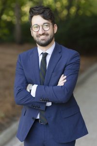 Photo of Harrison Stark, a young man with fair skin, a coarse short beard, and wavy, dark hair.