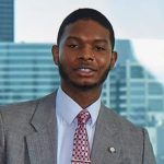 Close up photo of a black man in a gray suit