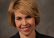 A woman with short blonde hair smiles.
