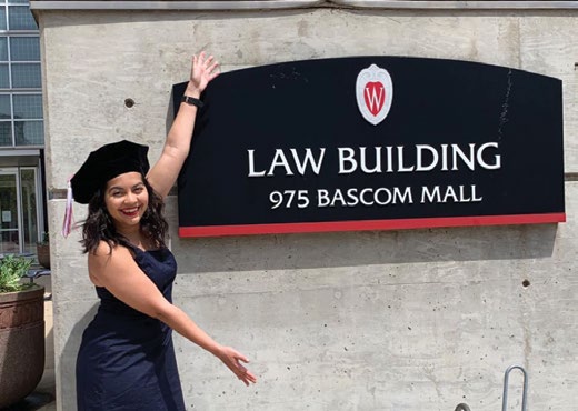 2020 graduate posing with law building sign