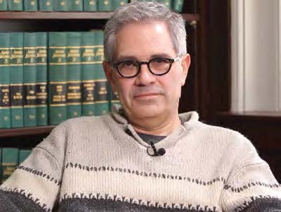 larry krasner sitting in front of a shelf of law books