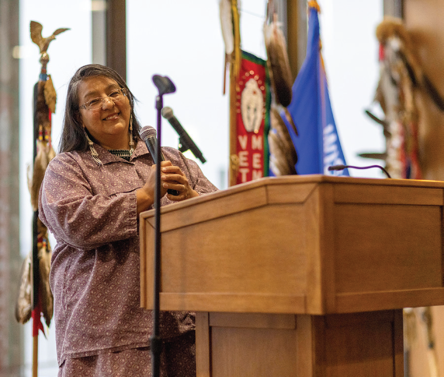 Person smiling at podium with microphone in hand.