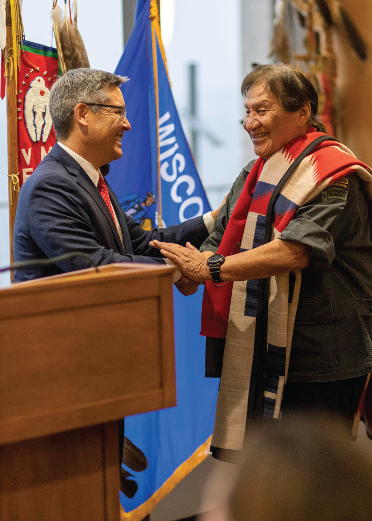 Dean Daniel Tokaji shakes another person's hand while standing at a podium.
