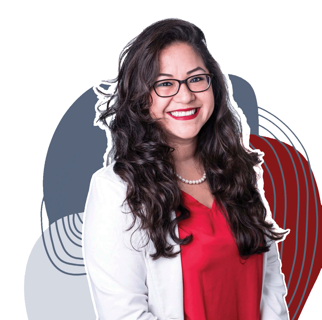 A photo of Angelica Guevara, an Hispanic woman smiling brightly at the camera, and she is wearing a white blazer with red top and white pearl necklace. Her brown hair is slightly curly and flows over her shoulders. She stands in front of abstract illustrations and has a happy and proud expression.