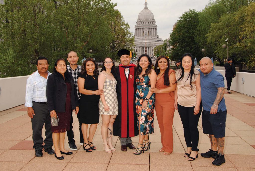 A diverse family takes a photo centered around a UW Law graduate in front of the state capitol building.