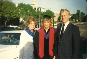 A photo of Laura Schumacher in a graduation gown with her mother and father in 1988.