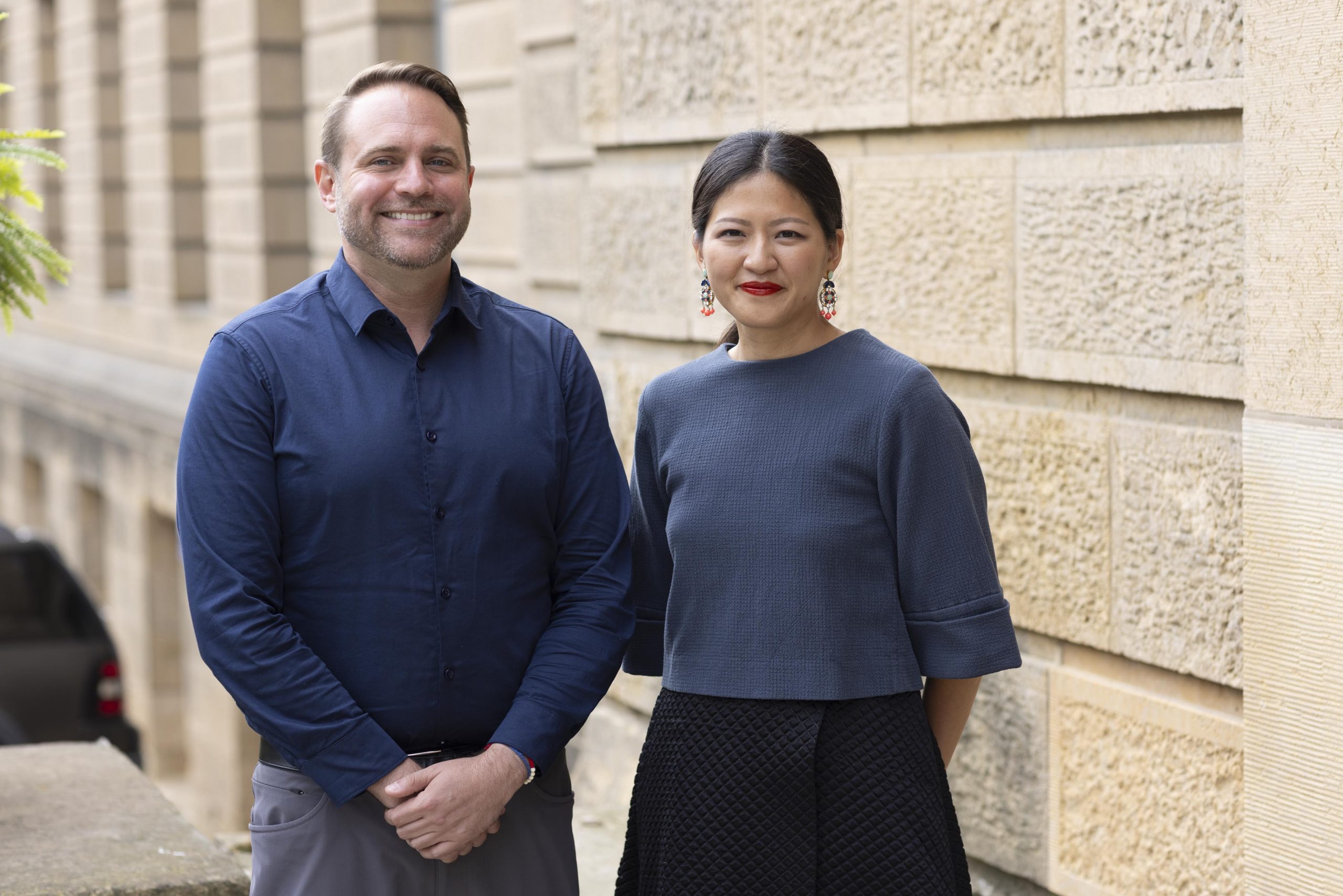 Jason Smith and Monique Lu stand together, smiling, both wearing a shade of blue.