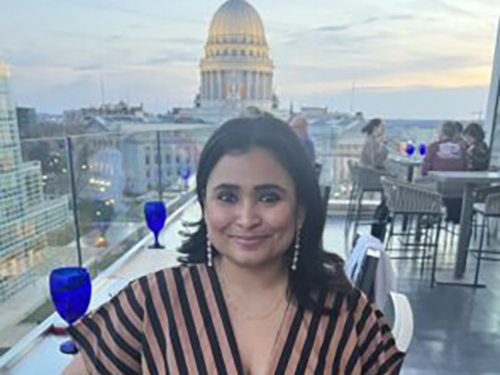 Photo of Ankita Bharadwaj standing in front of the Madison Capitol Building in the distance.