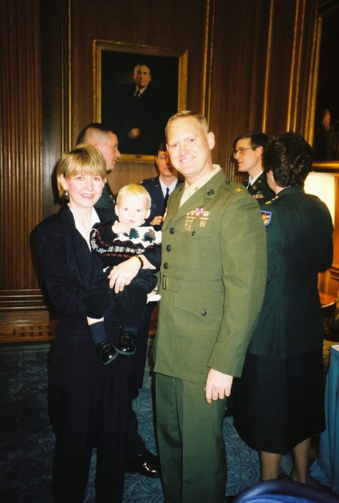Joan Stafslien holds baby Ben in her arms while standing beside her husband, Tom, who is in military dress uniform.