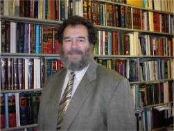 Photo of Alan Weisbard standing in front of a book shelf.