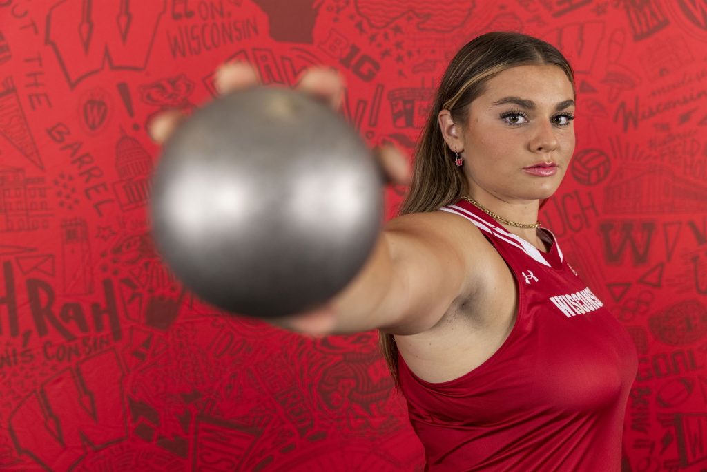 Danni Langseth holds a shotput close to the camera at a dramatic angle.