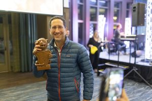 A man smiles while holding a miniature Gargoyle statue.