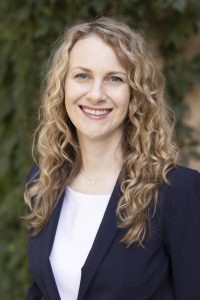 Headshot photo of Cecelia Kress, a white woman with curly blonde hair, fair skin, and blue eyes.