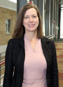 Headshot photo of Julie Baldwin, a white middle aged woman with shoulder length brown hair and blue eyes.