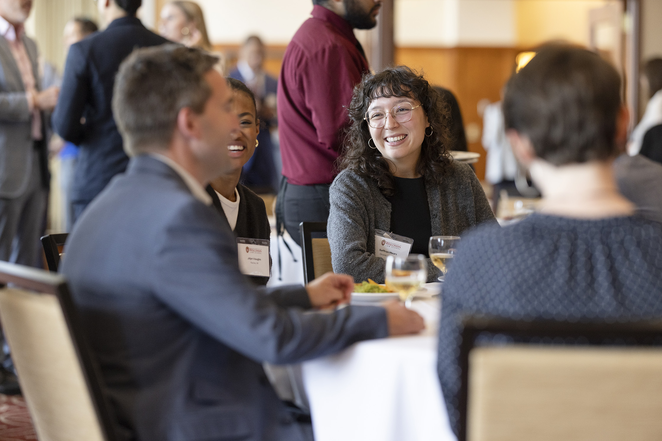 Several people laugh while seated at a table.