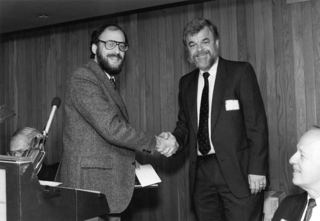 Two men shake hands in a black and white photo