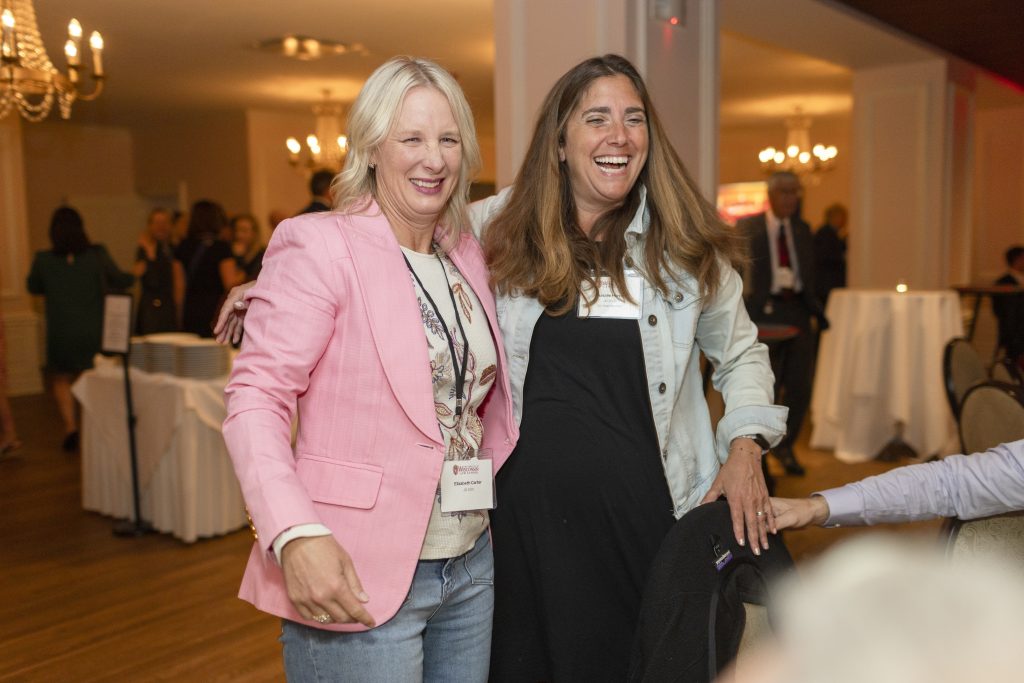 Two women laugh while standing together.