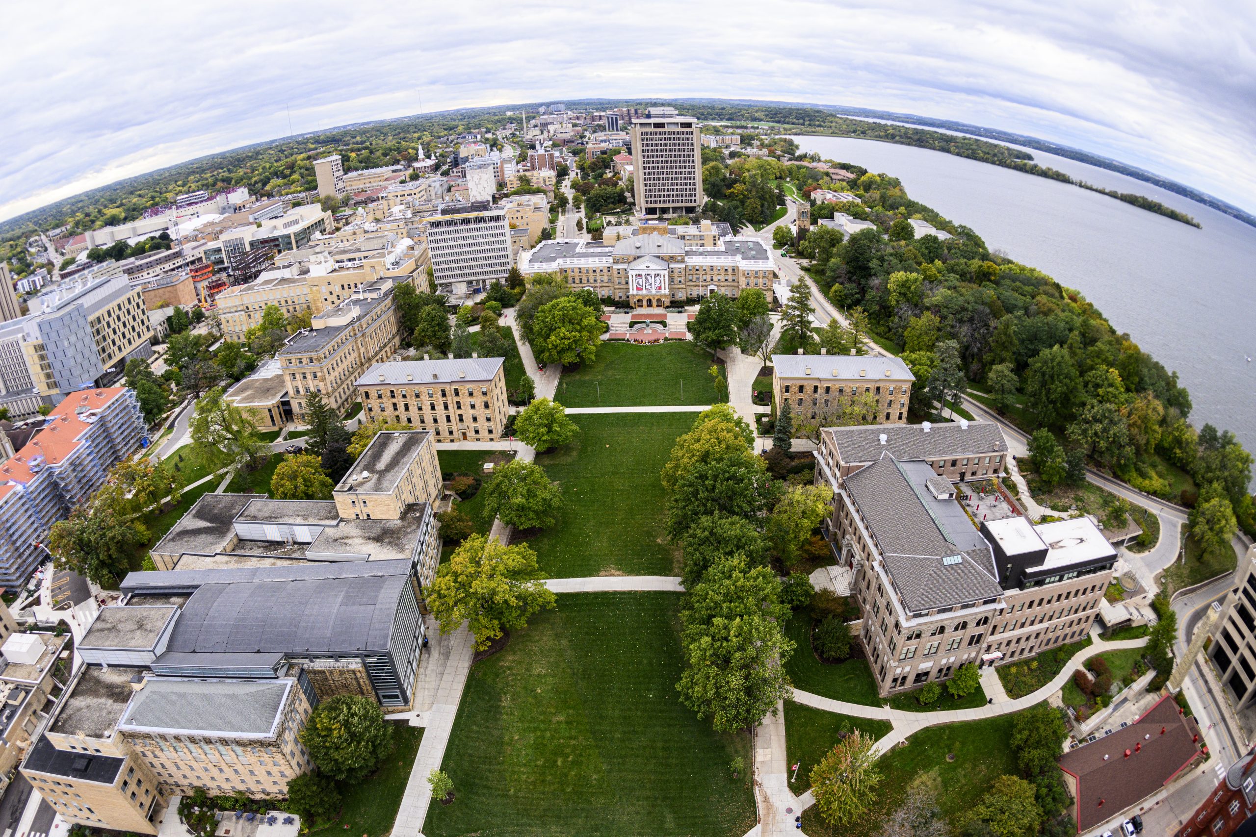 Bascom Hall, Bascom Hill and the central University of Wisconsin–Madison campus are pictured in an aerial view during autumn on Oct. 14, 2023. Major campus facilities clockwise from the bottom left include the Law School, South Hall, Birge Hall, Chamberlin Hall, Sterling Hall, Van Vleck Hall, Van Hise Hall, Sewell Social Sciences, Carillon Tower, North Hall and the Education Building. In the background at right is Lake Mendota and Picnic Point. The photograph was made with a fisheye lens from a helicopter looking west. (Photo by Jeff Miller / UW–Madison)