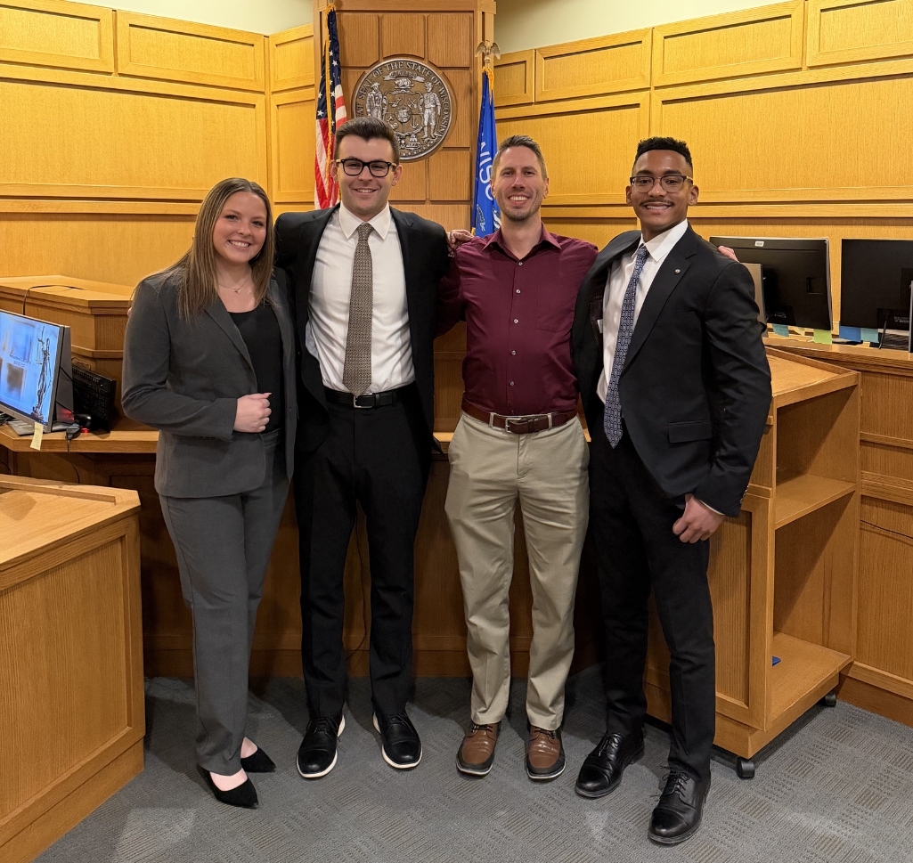 People stand together in front of a judge's bench.